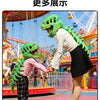 A person wearing a realistic green dinosaur skeleton costume interacts with a child in a colorful amusement park setting.
