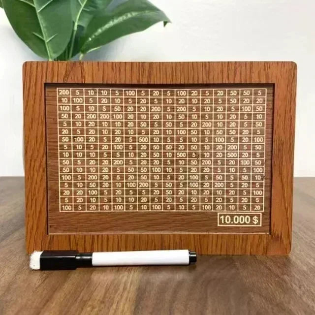 A wooden piggy bank with numbered slots for saving goals and a pen resting in front of it.
