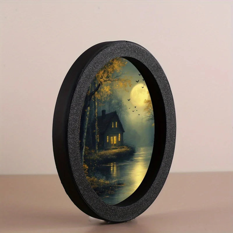 A round, black photo frame with a textured finish displaying a moonlit landscape scene.