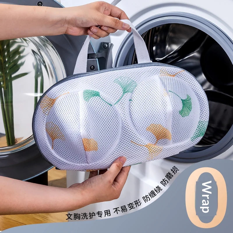 A hand is placing a mesh laundry bag for delicates into a washing machine drum.