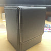 A dark gray PU leather magnetic card deck box is shown on a wooden surface.