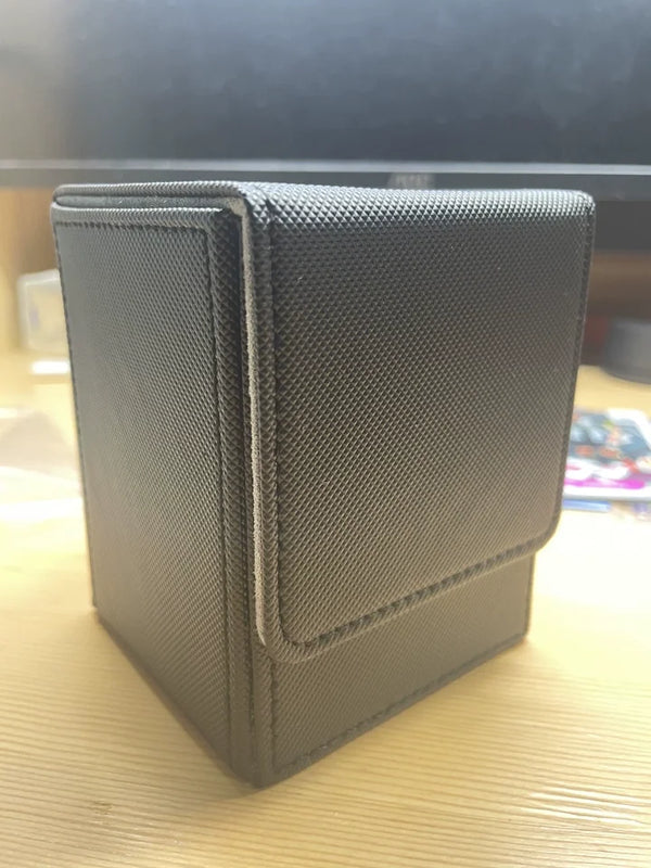 A dark gray PU leather magnetic card deck box is shown on a wooden surface.