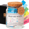 A glass jar filled with color-coded Bible verses and topped with a cork, packaged in a black box.