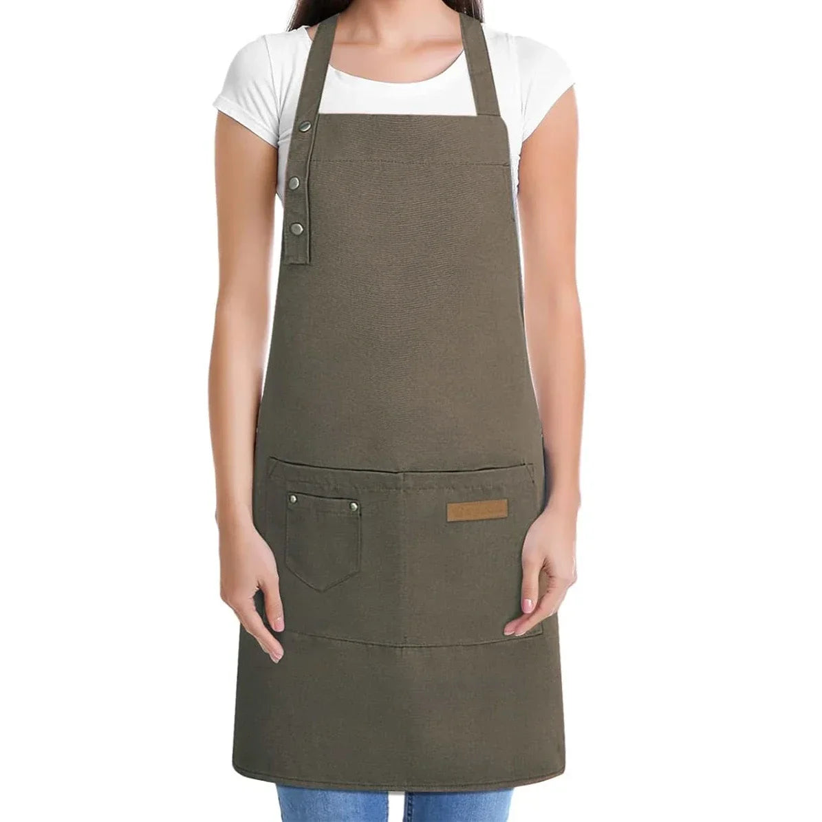 A woman wearing a dark olive green adjustable hairdressing apron over a white shirt.