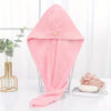 A pink microfiber hair drying wrap towel folded and displayed on a glass stand.