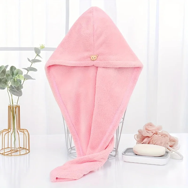 A pink microfiber hair drying wrap towel folded and displayed on a glass stand.