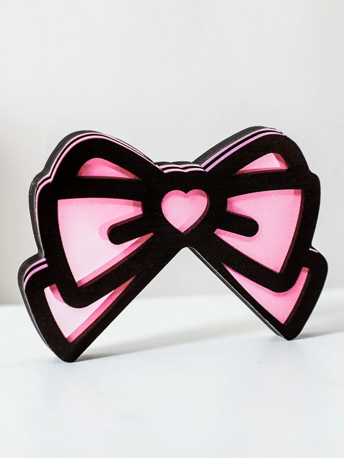 Décor d'écran en forme de nœud noir et rose avec détail de cœur.
