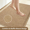 A beige waffle weave bathroom rug with a circular pattern is shown under bare feet.