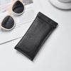 Black PU leather squeeze eyeglasses case with soft lining resting on a white surface.