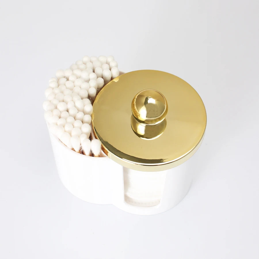 White plastic bathroom organizer with a gold lid holding cotton swabs and makeup accessories.