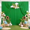 Fondo de tela verde exuberante con cortinas drapeadas, nubes blancas, flores rosas y detalles dorados, en una habitación lumi