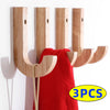 Three natural oak wood wall hooks with screws mounted on a white wall, shown next to a red towel.