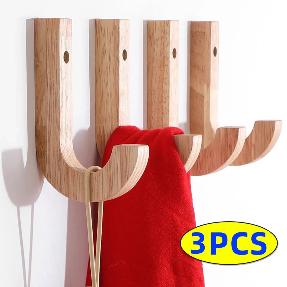 Three natural oak wood wall hooks with screws mounted on a white wall, shown next to a red towel.