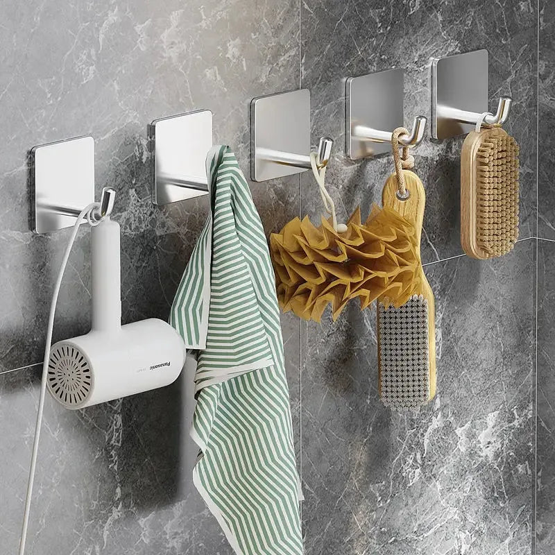 Stainless steel adhesive hooks hanging various items like a towel and a woven basket on a gray wall