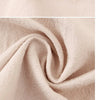 Close-up of a beige cotton kitchen apron fabric showing soft folds and texture.