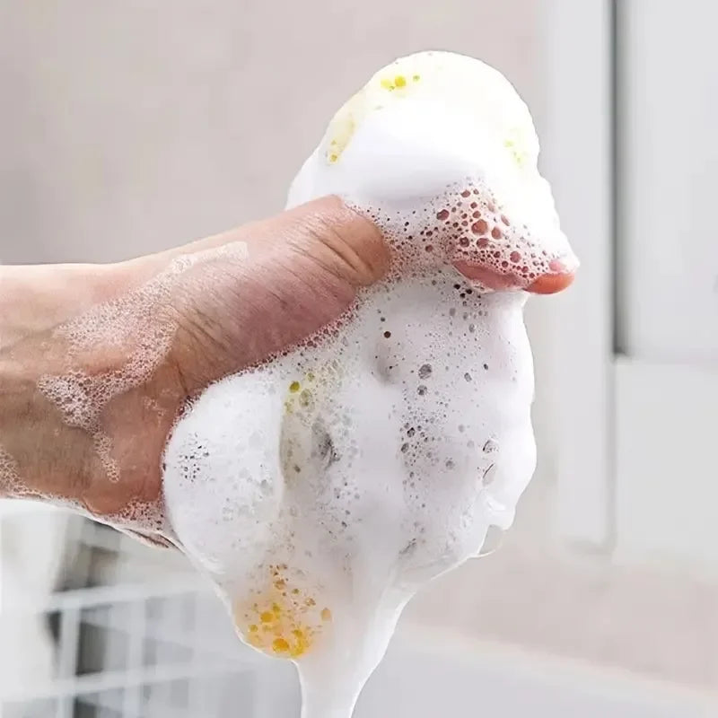 A hand is squeezing a white, bubbly cleaning towel or dish sponge.