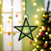 Forged iron star hanging candlestick with a green glass element, suspended against a blurred Christmas light background.