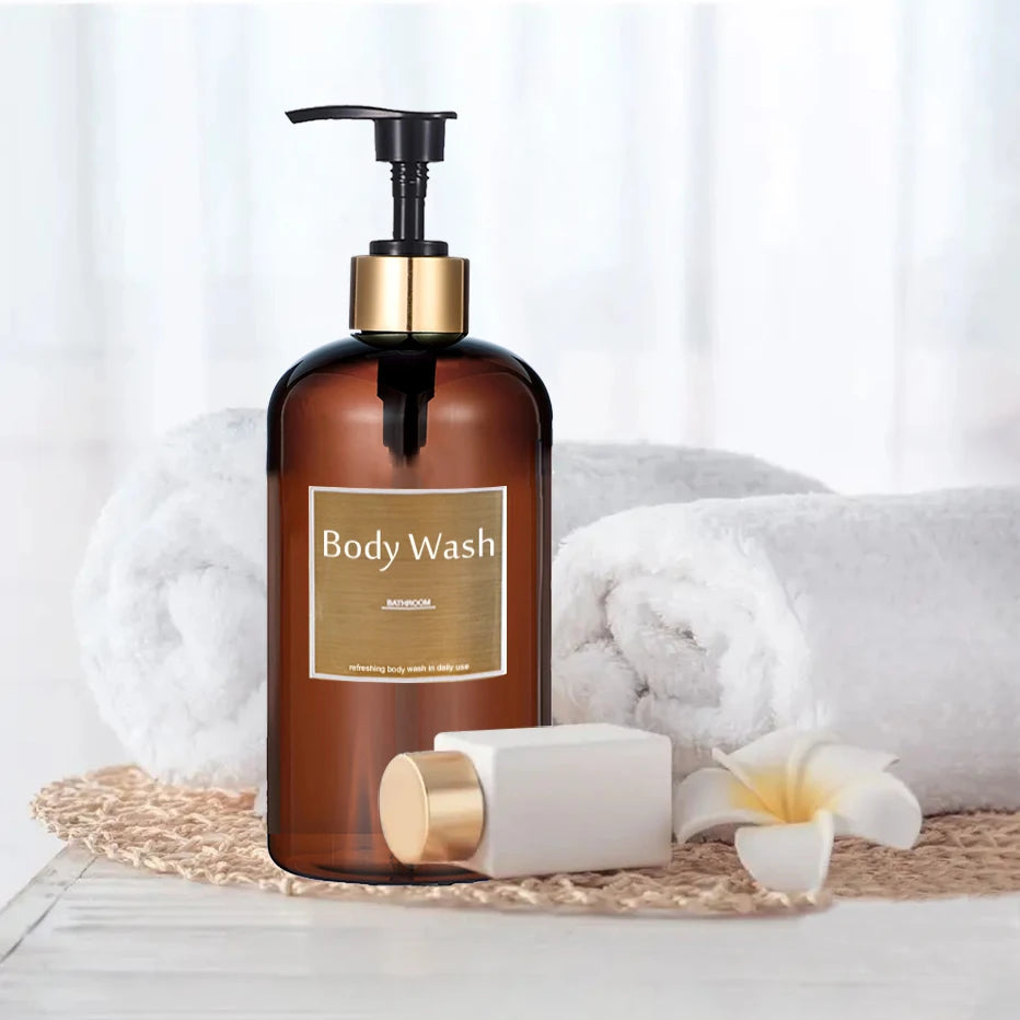A brown pump dispenser bottle of body wash sits on a white surface next to a white soap bar and white towels.