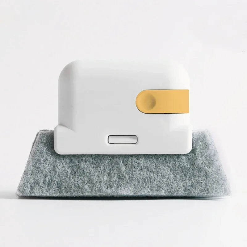 A white cleaning brush with a gold accent resting on a gray felt surface.