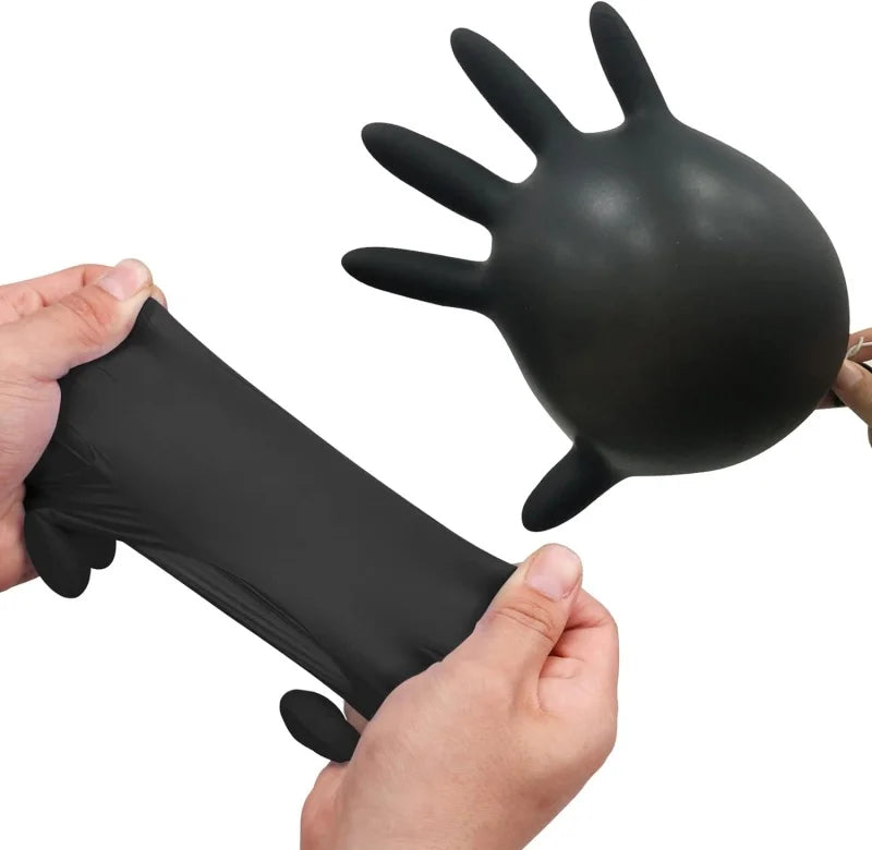 A hand is holding a black disposable nitrile cleaning glove, showing the size and texture of the glove.