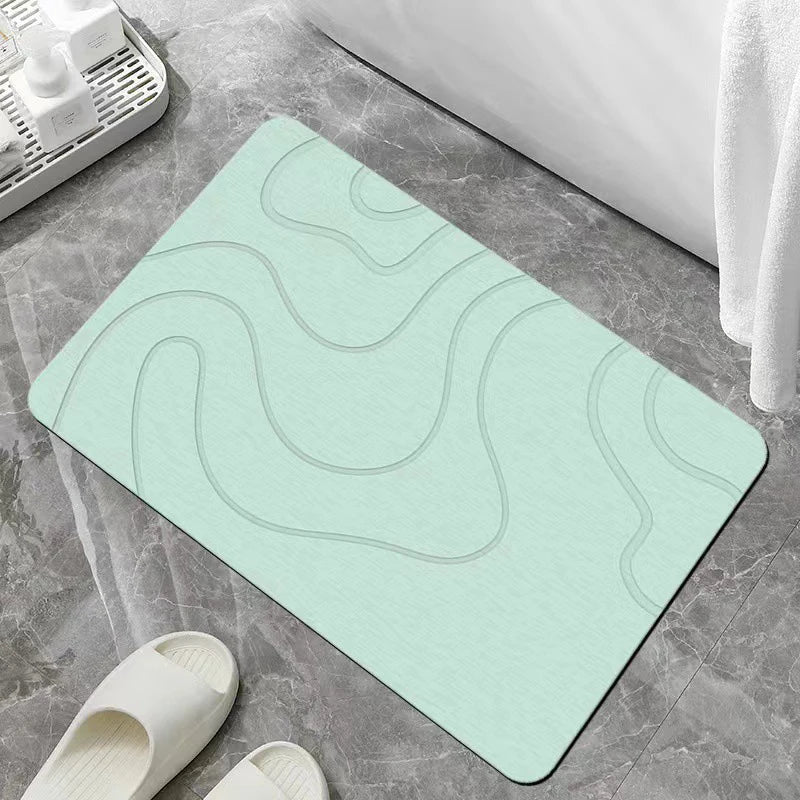 A light mint green bathroom mat with a wavy pattern is shown on a gray tile floor.