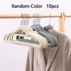 Ten random color velvet slim hangers hanging on a wooden rod next to a jacket.