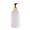 A white ceramic soap dispenser with a wooden pump top and a black pump mechanism.