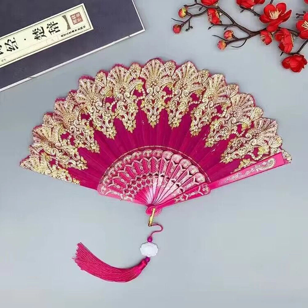 A vibrant pink and gold hand folding fan with intricate floral patterns.