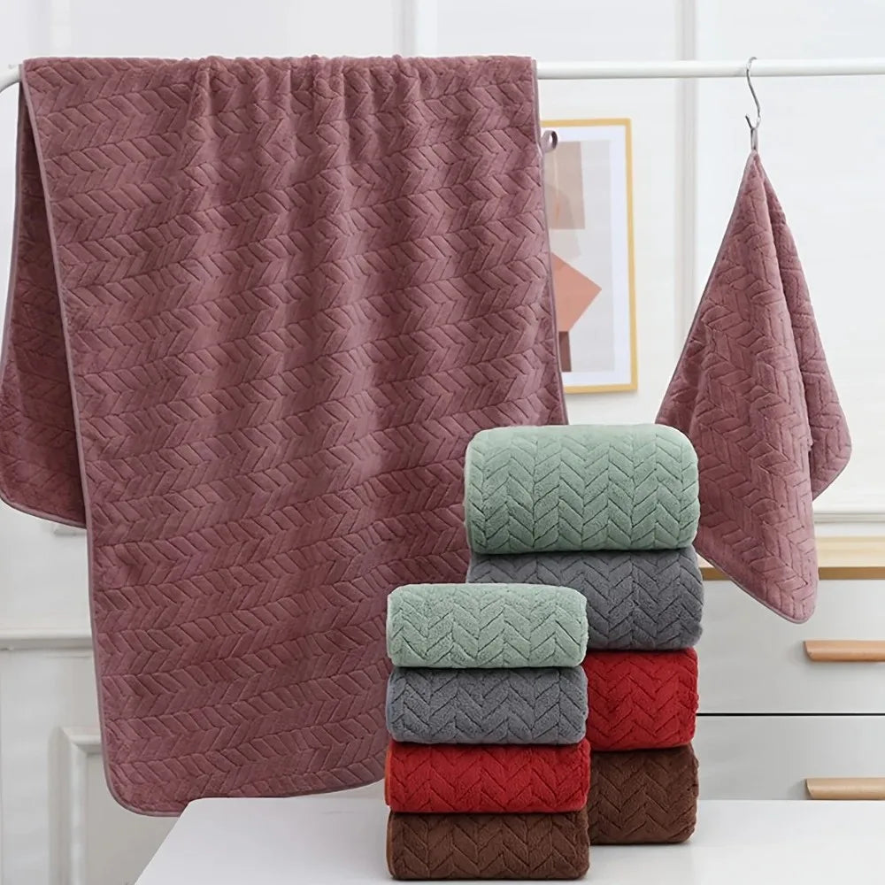 A stack of coral pink velvet bath towels hanging on a rack with a large towel draped nearby.