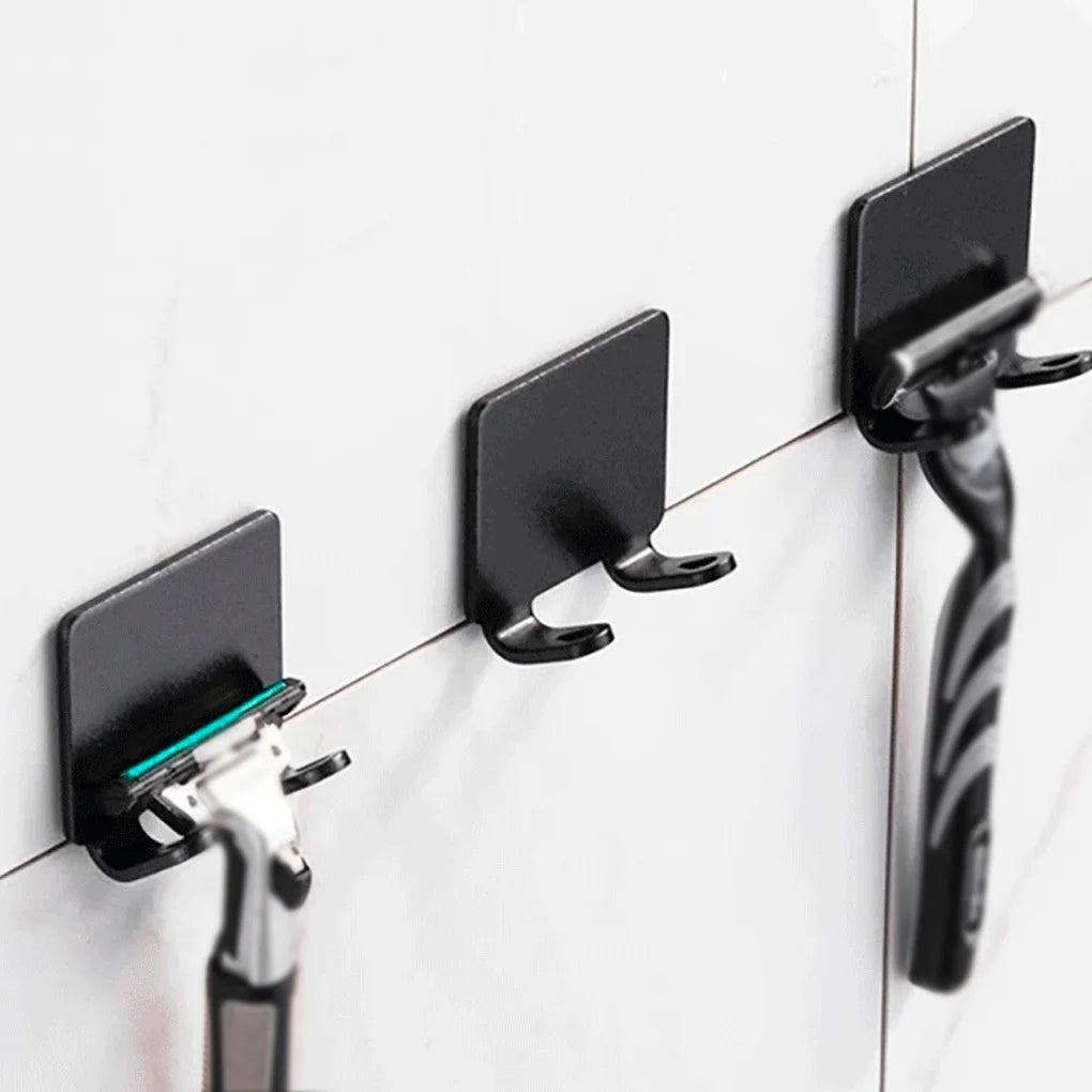 A black aluminum shaving razor storage rack mounted on a white tiled wall.