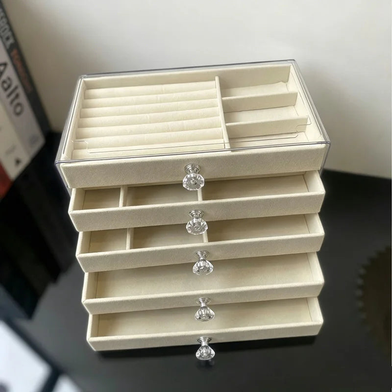 A clear acrylic 5-tier desktop jewelry organizer rack with light beige compartments and silver-toned jewelry stands.