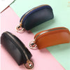 A set of two leather key organizer wallets, one navy blue and one tan brown, shown against a light pink and green background.