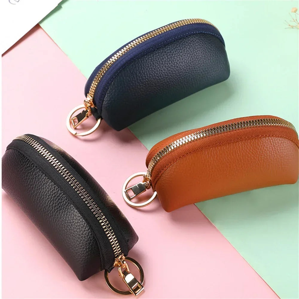 A set of two leather key organizer wallets, one navy blue and one tan brown, shown against a light pink and green background.