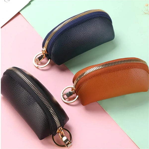 A set of two leather key organizer wallets, one navy blue and one tan brown, shown against a light pink and green background.