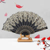 A black and gold ornate folding hand fan with intricate detailing displayed against a light gray background.