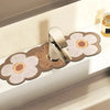 A modern silver faucet mat with a floral design is displayed on a white countertop.