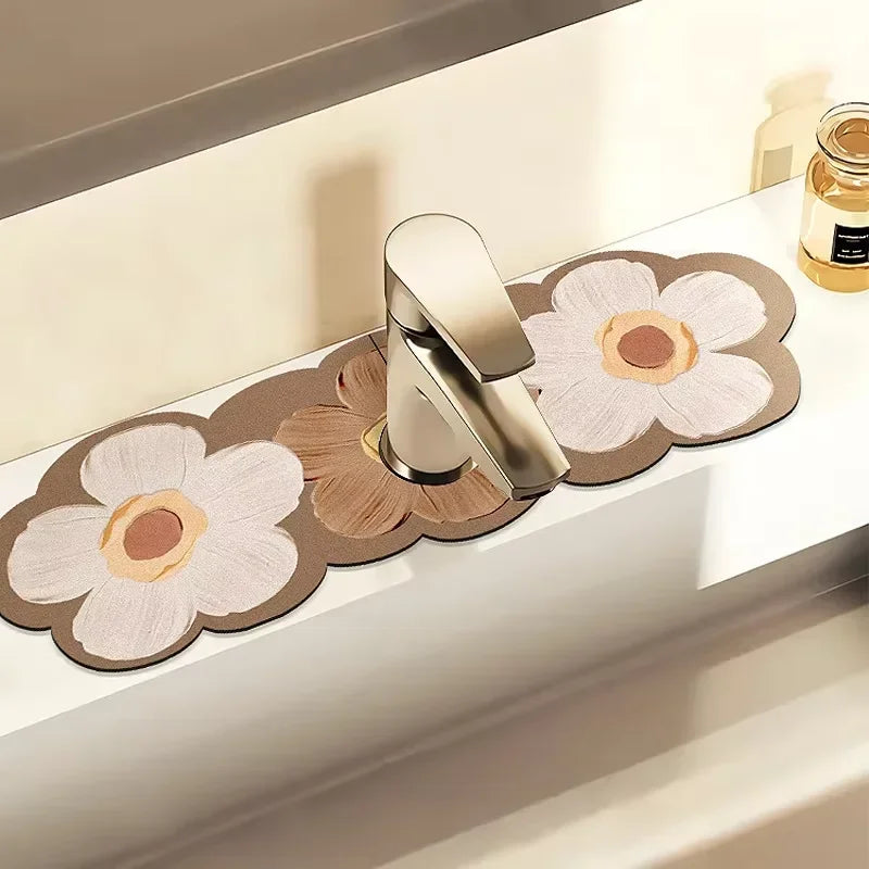 A modern silver faucet mat with a floral design is displayed on a white countertop.