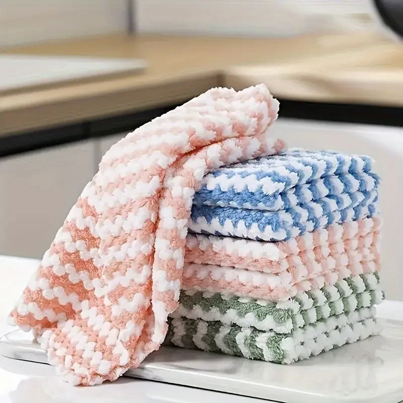 A stack of pink and blue coral fleece cleaning cloths resting on a white surface.
