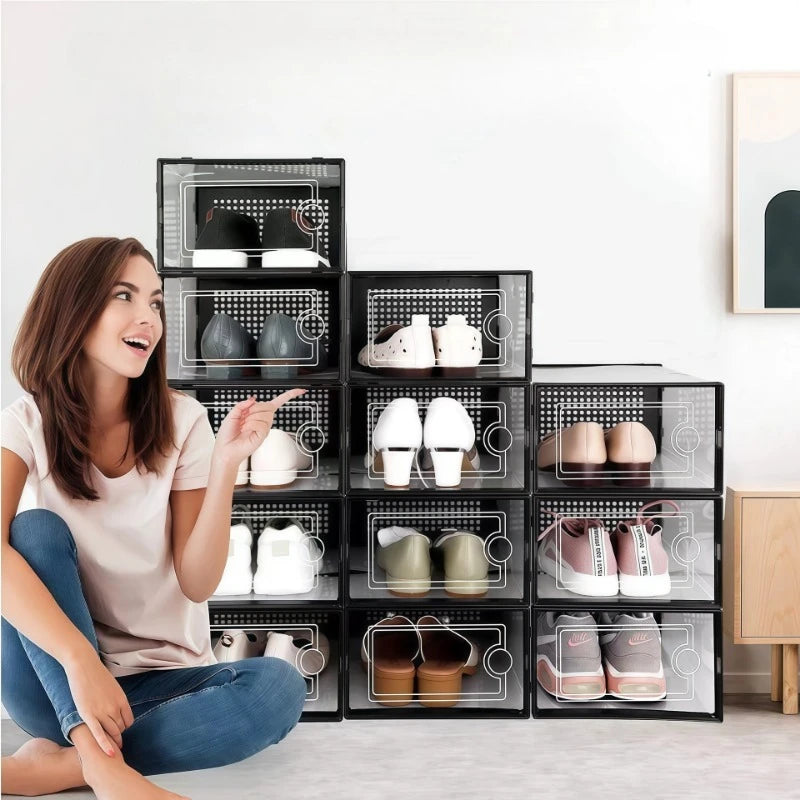 A woman is looking at a stack of twelve clear plastic shoe storage boxes with front doors on a white shelf.