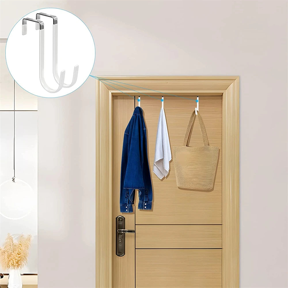 Four non-slip over-the-door hooks are installed on a wooden door for hanging items like towels and bags.