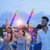 Eine Gruppe feiert mit leuchtenden LED-Glowsticks bei Dämmerung.