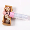 A pink automatic transparent folding umbrella with a cork handle and coiled cord is shown in a wooden box.