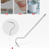Stainless steel reusable toothpick with a curved tip shown next to cosmetic items.