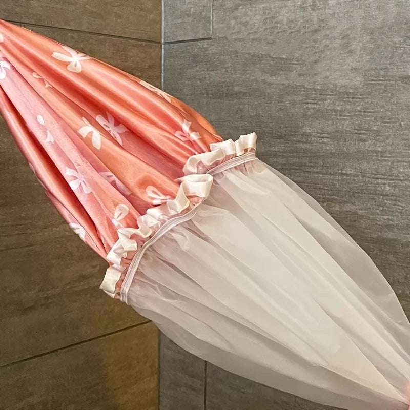A pink and white reusable double layer shower cap with a ruffled edge