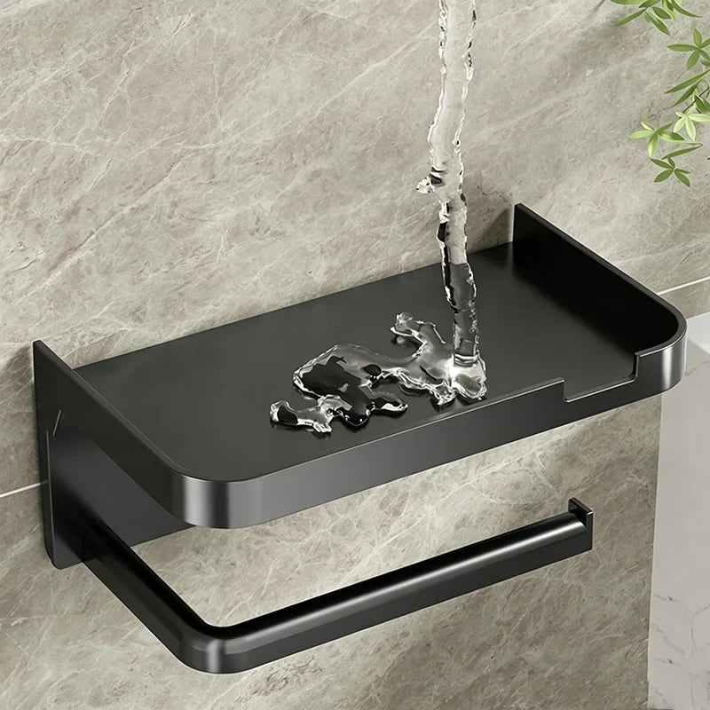 A black no-drill toilet paper holder with a storage shelf mounted on a wall, featuring a dripping water effect.