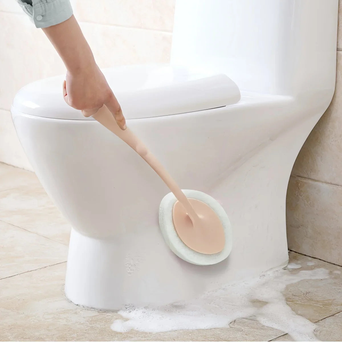 Eine Hand benutzt eine lange Reinigungsspongebürste, um das Innere einer weißen Toilettenschüssel zu reinigen.