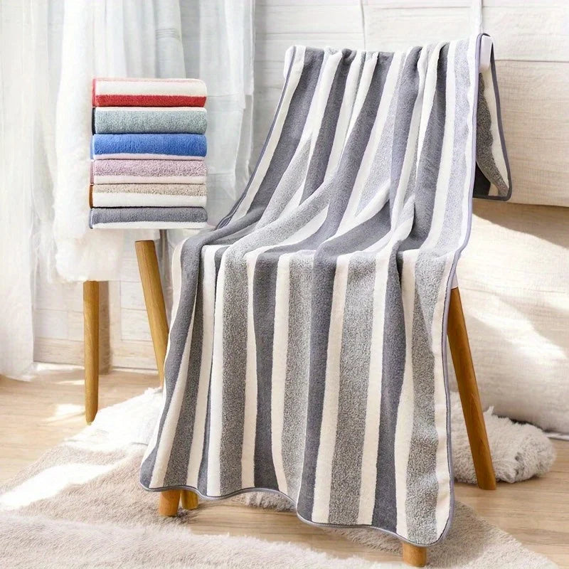 A gray and white striped microfiber bath towel draped over a wooden stand.