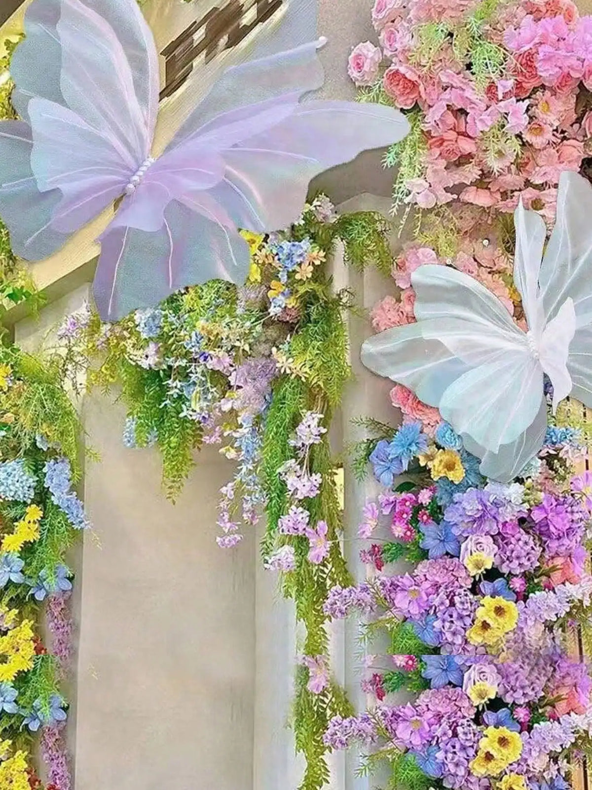 A vertical floral arrangement featuring pink and purple flowers and large, translucent butterfly decorations.
