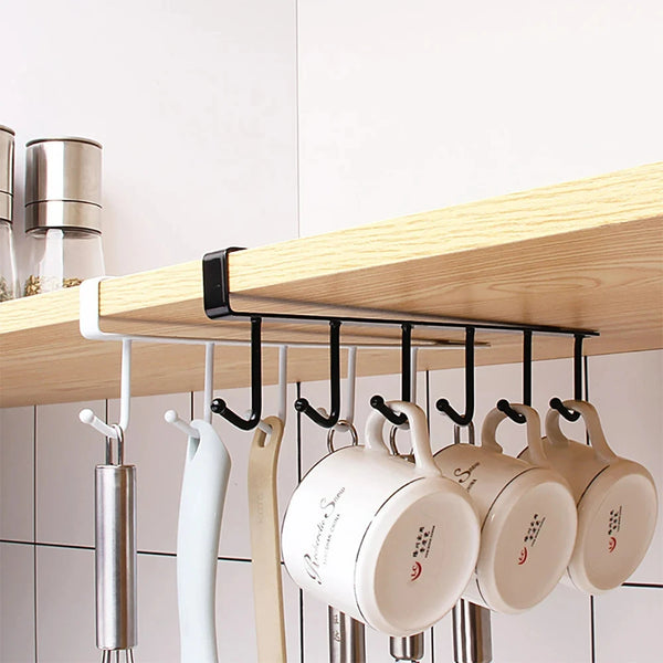 A wooden shelf with black hooks holding several white ceramic mugs and a stainless steel utensil holder.