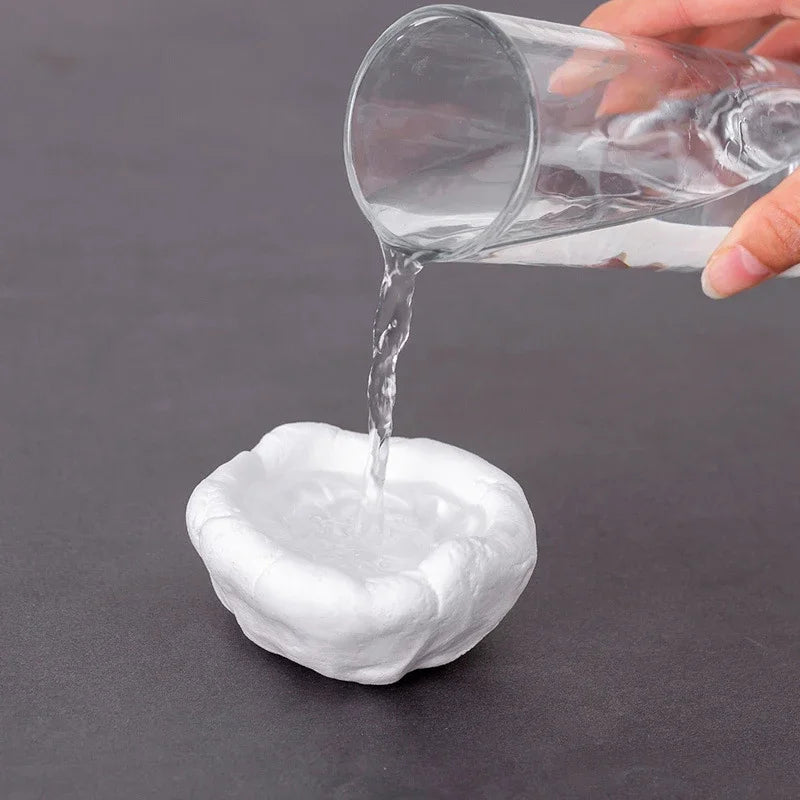 A hand pours clear liquid from a glass into a white clay plug to demonstrate sealant.